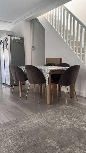 Ein Essbereich mit Tisch und Stühlen, einer Treppe und einem Kühlschrank.