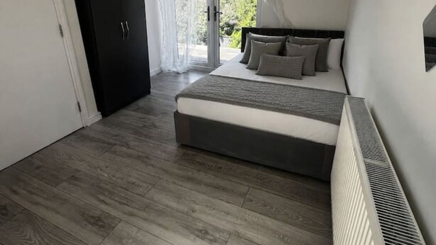 Ein Schlafzimmer mit einem Bett, einem Heizkörper, einem Kleiderschrank und einer Glastür zum Außenbereich.