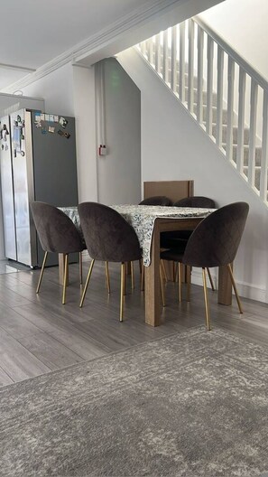 Ein Essbereich mit Tisch, Stühlen, einer Treppe und einem Kühlschrank.