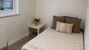 A bedroom with a bed, a nightstand, a window, and a ceiling light. - Spacious Room Perfect for Contractors Couples Solo Travellers (Greenford)