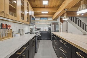 A modern kitchen with wooden cabinets, a stainless steel refrigerator, and a marble countertop. - Fir Sure Chalet - Dog friendly modern cabin in SLT (South Lake Tahoe)