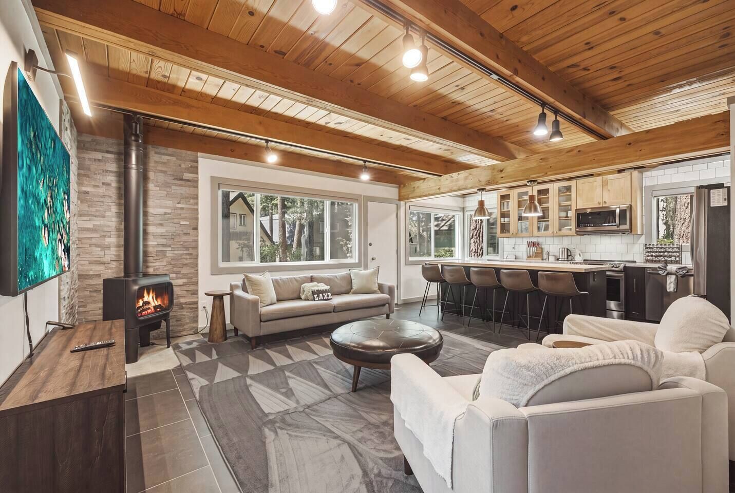 Una sala de estar moderna con chimenea, un sofá, una mesita de centro y una zona de cocina con taburetes de bar.