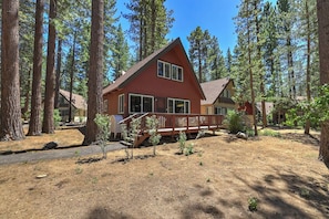 A cabin with a wooden deck, surrounded by tall pine trees. - Fir Sure Chalet - Dog friendly modern cabin in SLT (South Lake Tahoe)