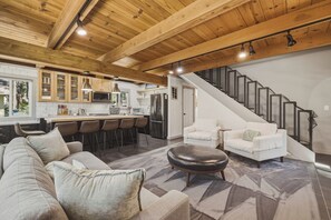 A modern living room with a sofa, ottoman, and a staircase leading to an upper level. - Fir Sure Chalet - Dog friendly modern cabin in SLT (South Lake Tahoe)