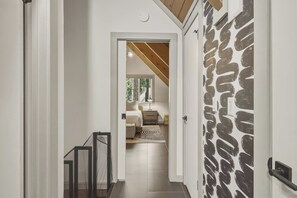 A hallway leading to a bedroom with a bed, a nightstand, and a window. - Fir Sure Chalet - Dog friendly modern cabin in SLT (South Lake Tahoe)