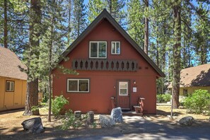A two-story red building with a gabled roof, a front porch, and a small stone statue in front. - Fir Sure Chalet - Dog friendly modern cabin in SLT (South Lake Tahoe)