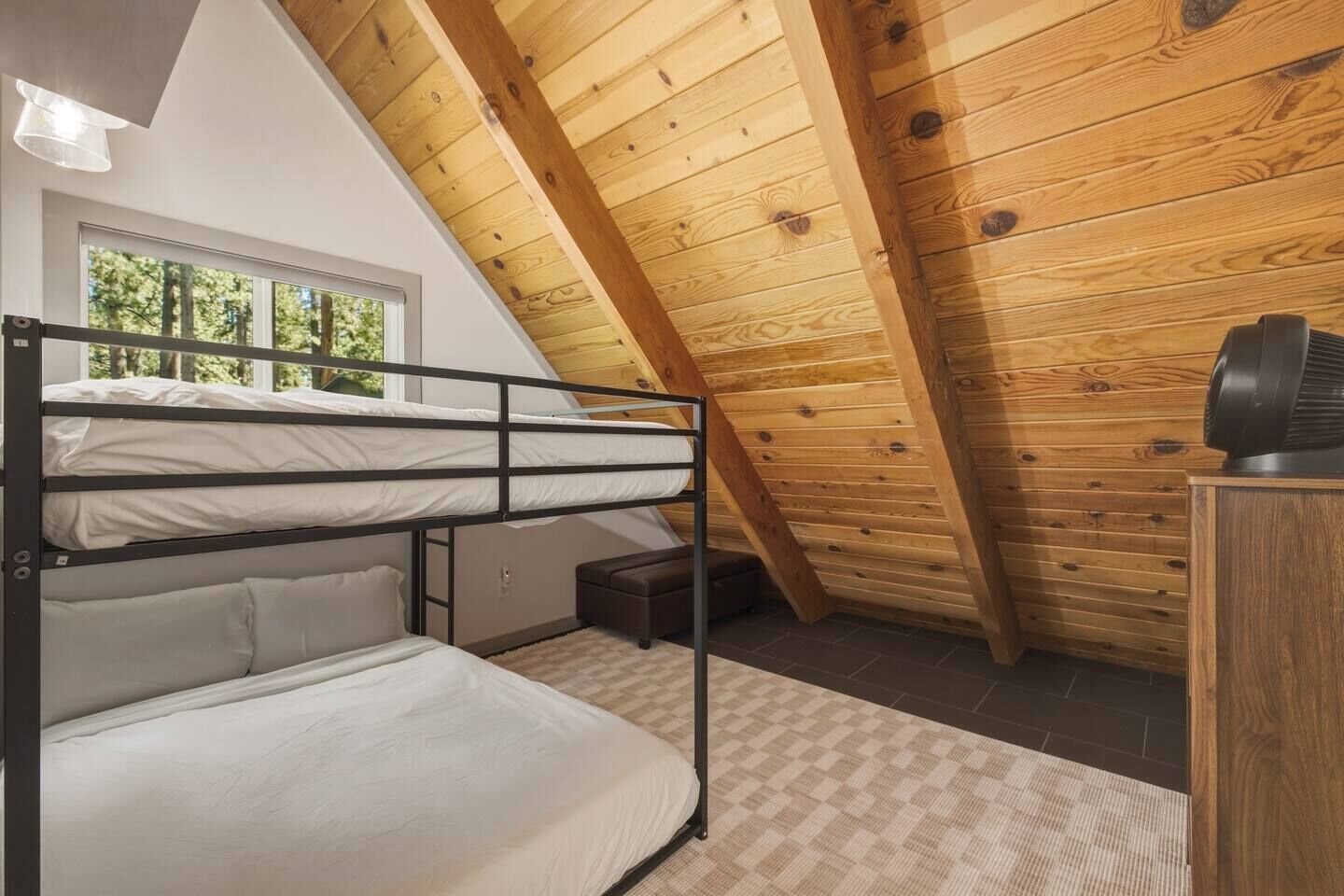 Quarto com beliche, teto inclinado e janela.