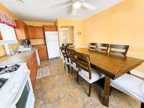A compact kitchen with a dining area, featuring a stove, refrigerator, and wooden cabinets. - Beach Getaway 3BR • Parking • Beach Badges (Seaside Heights)