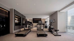 A modern home gym with treadmills, a stationary bike, and a TV screen. - Yantai First Beach Seaview Yaduo Hotel (Yantai)