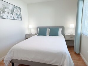 Een slaapkamer met een bed, twee nachtkastjes en een bijzetmeubel.