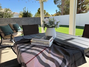 An outdoor patio with a table, chairs, and a book stack. - Modern 3BR Single-Story Home with Spacious Yard (North Las Vegas)