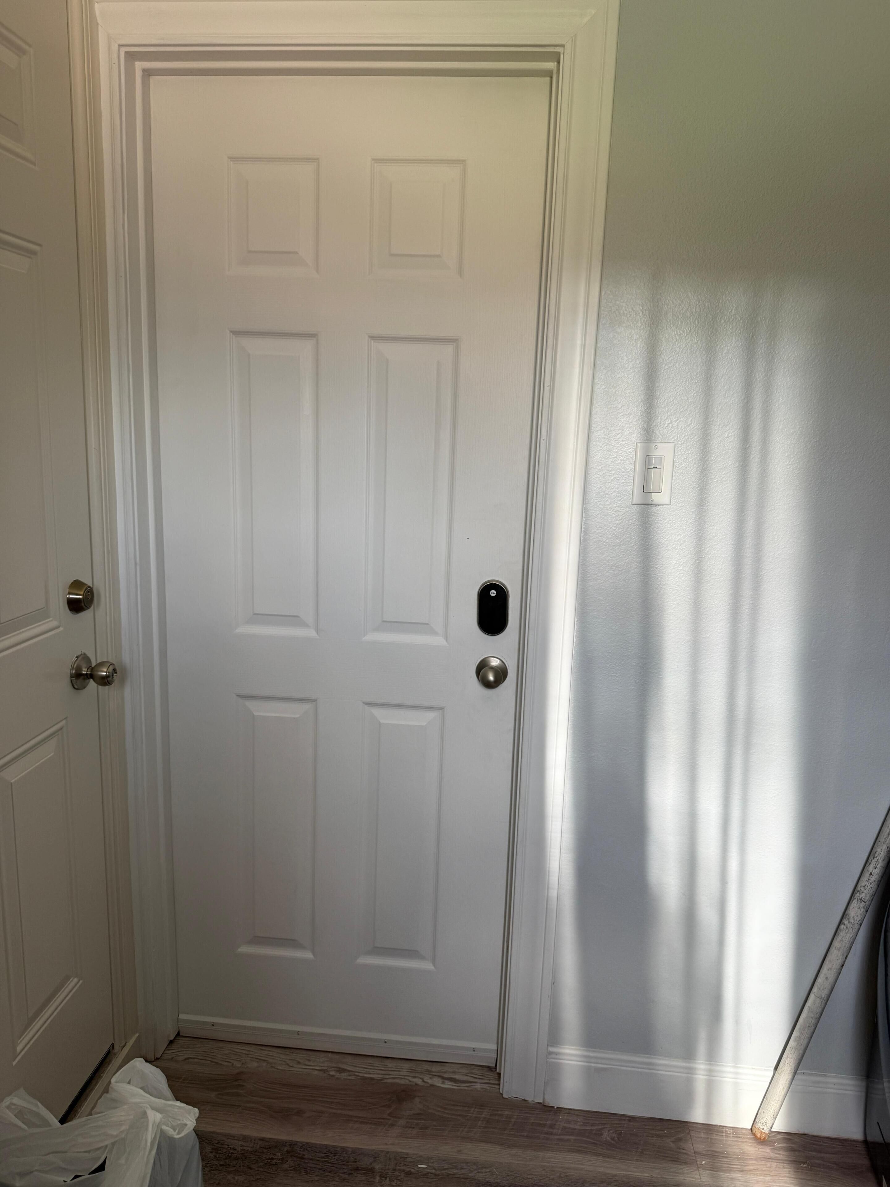 Puerta blanca cerrada con un ojo de cerradura y un timbre.
