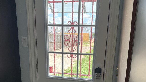 Una puerta blanca con un panel de vidrio y una rejilla metálica decorativa.