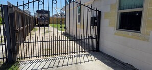 A gated driveway leading to a building with a window and a door. - Private Luxury Apartment Near IKEA, Gated Parking (Houston)