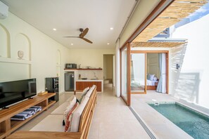 A modern living room with a TV, seating area, kitchen, and a pool. - Villa Aurora Canggu (Canggu)