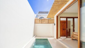 A modern pool area with a clear blue pool, a wooden deck, and a glass door leading to a room. - Villa Aurora Canggu (Canggu)