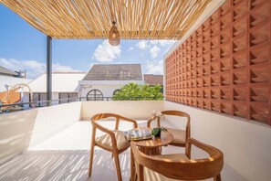 A rooftop terrace with a wooden table and chairs, a woven ceiling, and a brick wall with geometric patterns. - Villa Aurora Canggu (Canggu)