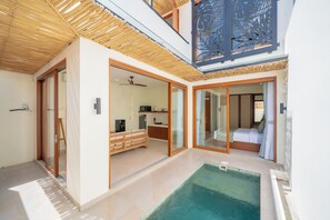A modern interior with a pool, wooden ceiling, and a kitchen area. - Villa Aurora Canggu (Canggu)
