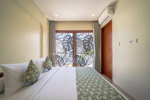 A hotel room with a bed, curtains, an air conditioning unit, and a view through a window with a leaf pattern. - Villa Aurora Canggu (Canggu)
