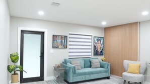 Una sala de estar moderna con un sofá, una silla, una mesita y una planta en maceta.