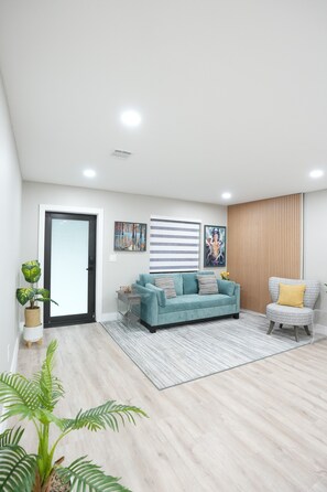A modern living room with a sofa, a chair, a small table, and a potted plant. - Mango Tree House (Hialeah)