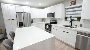 Una cocina moderna con armarios blancos, electrodomésticos de acero inoxidable y una isla central.