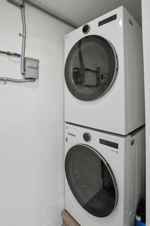 Two stacked laundry machines in a room with white walls. - Mango Tree House (Hialeah)