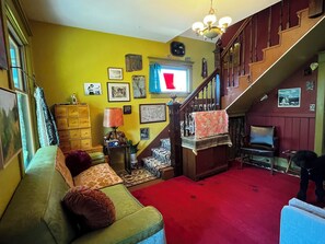 Ein Zimmer mit Treppe, einer Couch, einer Lampe und verschiedenen Wandgestaltungen.