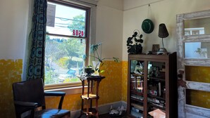 A room with a window, a chair, a bookshelf, and a lamp. - Art filled 1908 house in Columbia City, close to Light Rail. Cozy, relaxing, fun (Seattle)