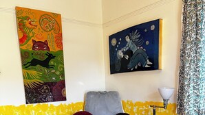 A room with a sofa, a small table, a lamp, and two paintings on the wall. - Art filled 1908 house in Columbia City, close to Light Rail. Cozy, relaxing, fun (Seattle)