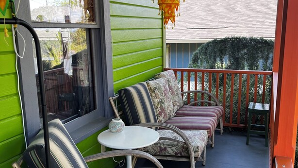 A porch with wicker furniture, a small table, and a hanging lantern. - Art filled 1908 house in Columbia City, close to Light Rail. Cozy, relaxing, fun (Seattle)