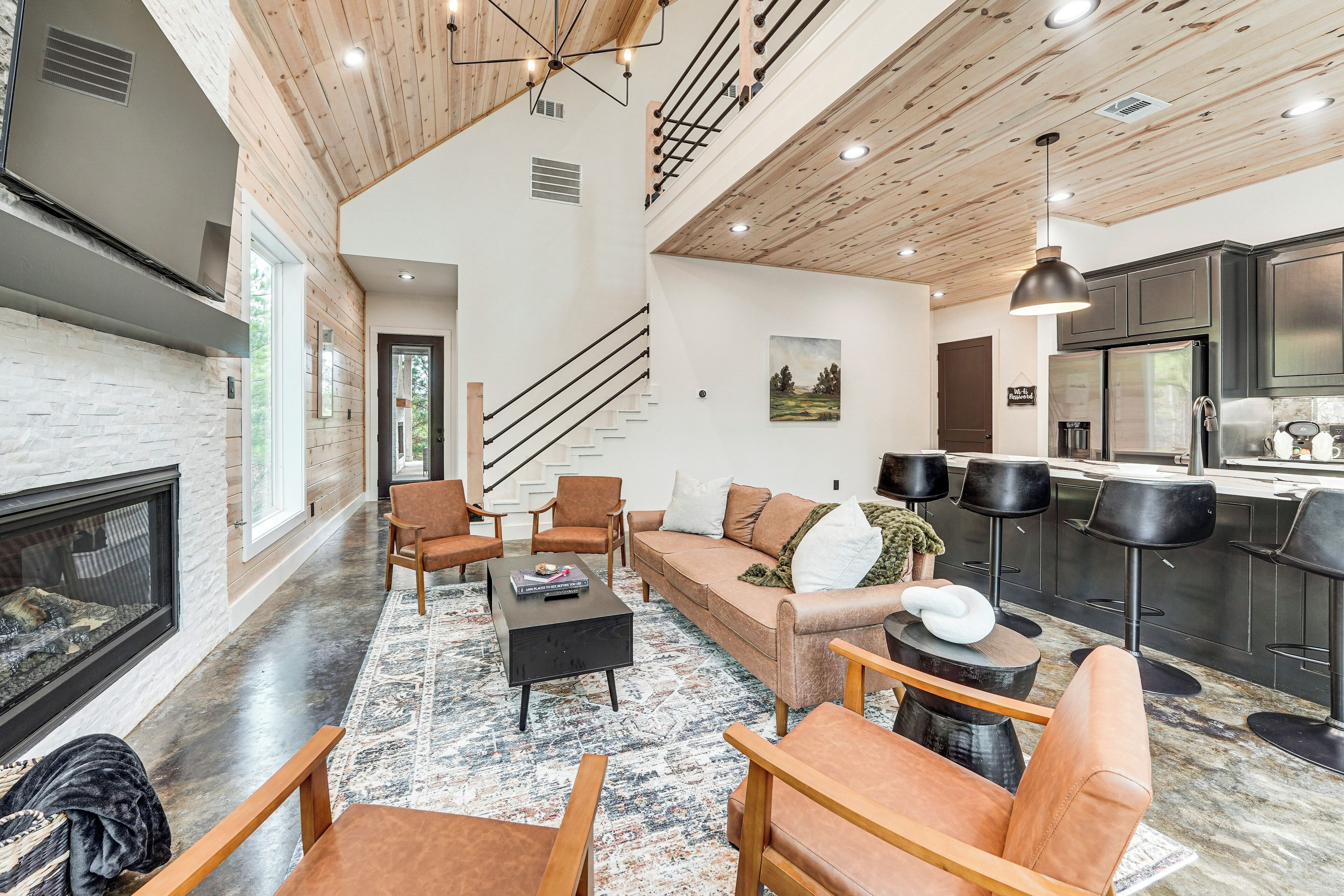 A spacious living area with a fireplace, comfortable seating, a kitchen with modern appliances, and a staircase leading to another level.
