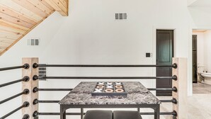 Un ring de boxeo con una mesa de mármol en el centro, vigas de madera en el techo y una puerta al fondo.