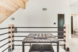 Ein Boxring mit einem Marmortisch in der Mitte, Holzbalken an der Decke und einer Tür im Hintergrund.