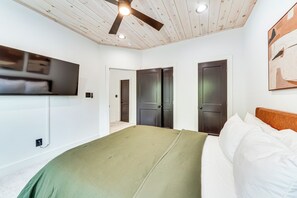 Ein Schlafzimmer mit einem Bett, einem Deckenventilator, einem Fernseher und zwei Türen.