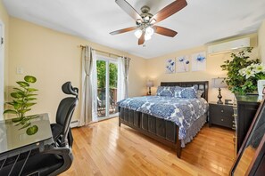 A bedroom with a bed, a desk, a chair, a ceiling fan, and a window with curtains. - Charming 3BR Home Near NYC  Free Parking (JERSEY CITY)