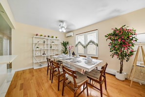 A dining area with a white table set for four, surrounded by wooden chairs. - Charming 3BR Home Near NYC  Free Parking (JERSEY CITY)
