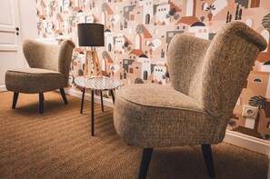 A room with a patterned wallpaper, two armchairs, a small round table, and a floor lamp. - Le Refuge de Lamartine Room (FUISSE)