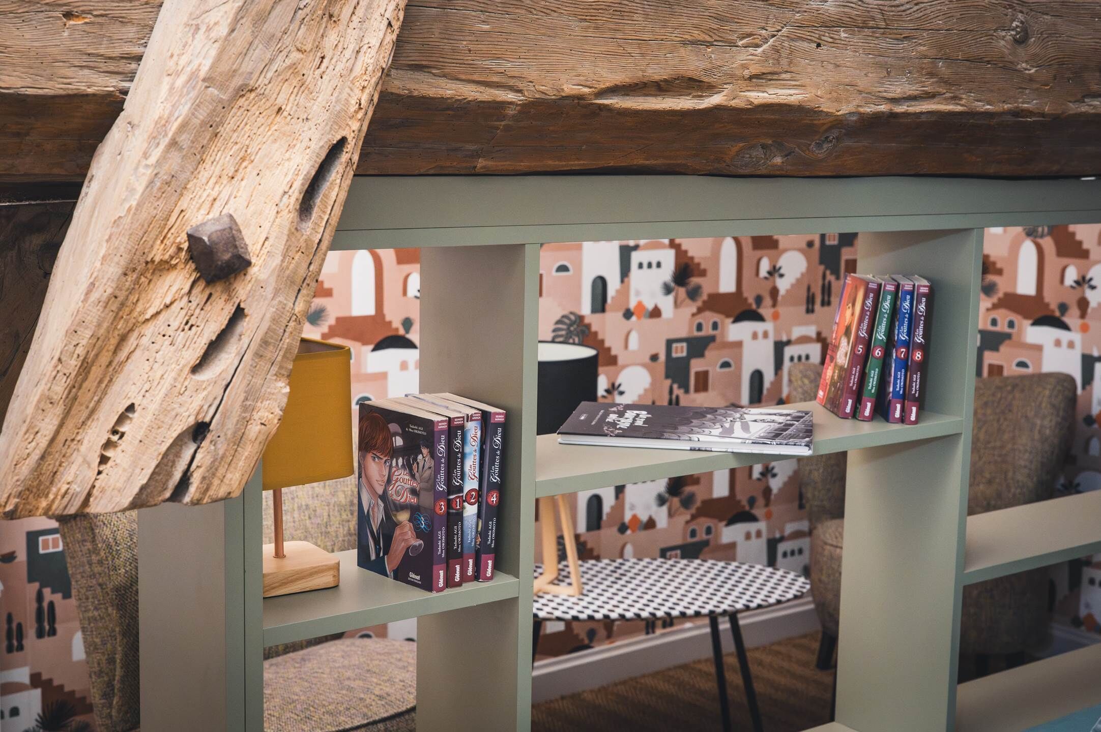 Una libreria con libri e un piccolo tavolo, con una parete decorata da un motivo.
