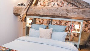 Une chambre à coucher avec un lit, des oreillers, une table de chevet, une lampe et une chaise.