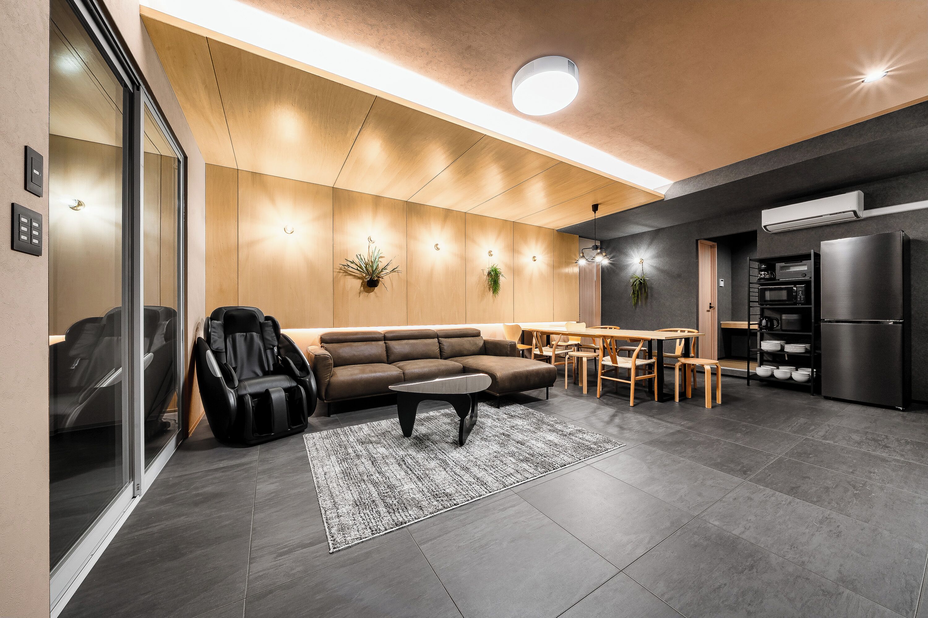 Una sala de estar moderna con un sofá, sillón de masaje y una zona de comedor con mesa y sillas.