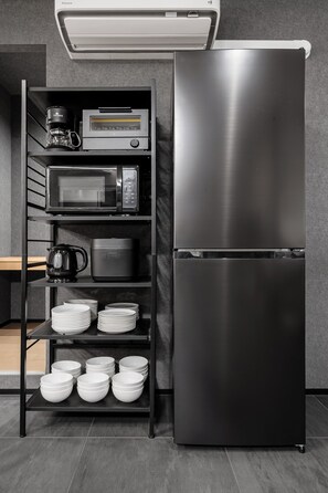 A kitchen with a stainless steel refrigerator, a coffee maker, a microwave, and shelves with plates and bowls. - THE AURUM (Asahikawa)