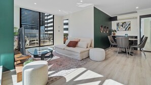 Una sala de estar moderna con un sofá, una mesa de centro de vidrio y un comedor con sillas.