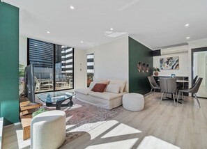 Ein modernes Wohnzimmer mit einer Couch, einem Glastisch und einem Essbereich mit Stühlen.