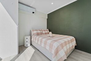 A modern bedroom with a bed, a bedside lamp, and a wall-mounted air conditioner. - Newly Renovated Spacious Apartment (North Sydney)