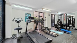 Un gimnasio con cintas de correr, bicicletas estáticas y equipo de levantamiento de pesas.