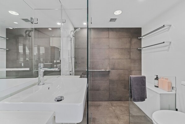 A modern bathroom with a glass-enclosed shower, a large white sink, and a toilet. - Newly Renovated Spacious Apartment (North Sydney)