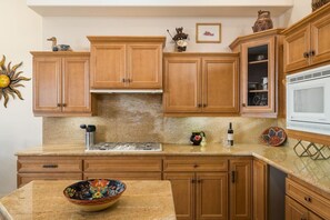 A kitchen with wooden cabinets, a granite countertop, a microwave, and various kitchen items. - Sedona Jewel | Panoramic Views, Patio, Hot Tub (Sedona)
