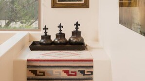A room with a window, a painting of a sunset, a decorative tray with vases, and a patterned rug. - Sedona Jewel | Panoramic Views, Patio, Hot Tub (Sedona)