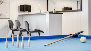 A pool table with a cue stick and billiard balls, a blue felt surface, and a white wall with a decorative item. - Cozy home in Stege with sauna (Stege)